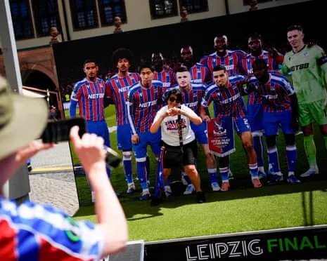 A Crystal Palace fan poses with a giant team photo in Leipzig