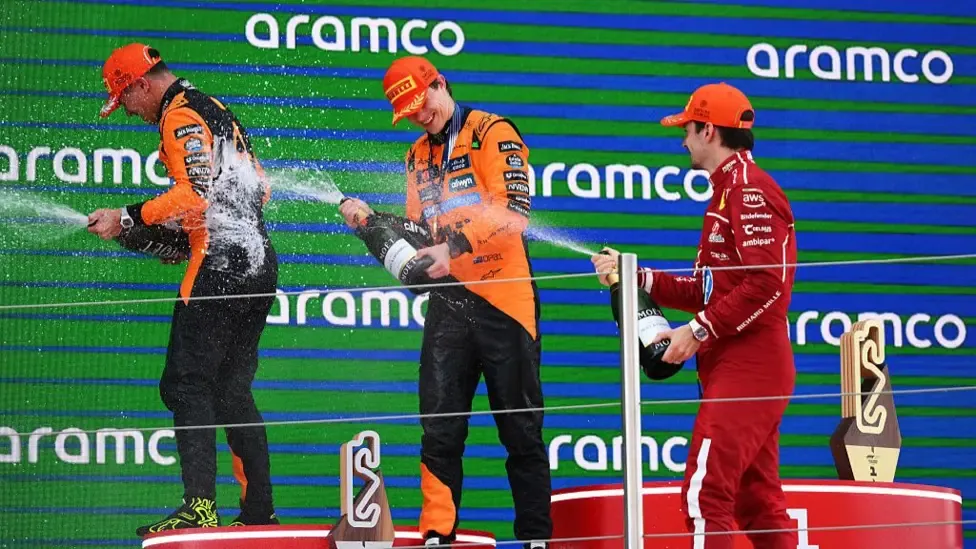 Oscar Piastri, Lando Norris and Charles Leclerc spraying each other with champagne on the podium at the Barcelona Grand Prix